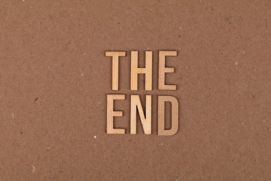 A close-up view of four wooden letter tiles on a brown cardboard background spell out 'THE END'. The tiles are arranged in two rows, with 'THE' on top and 'END' below, and are evenly spaced. This image is taken in natural lighting, highlighting the texture of the wooden tiles and the matte surface of the cardboard, which is typical of packing materials used during home relocation. The setting suggests preparation or completion of a moving process, with the tiles possibly symbolising the final stage of a move or packing. In the context of house removals and furniture transport, this visual could imply the conclusion of a furniture loading or packing and moving session by Man with Van Ponders End. The overall scene emphasizes careful handling and packing materials like cardboard, which are essential elements in professional removals services.